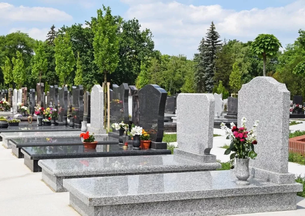 Pierres tombales en granit alignées dans un cimetière paysager`